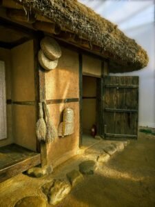 Traditional Korean hanok with straw roof and wooden door in Gyeonggi, South Korea, capturing rustic architecture.