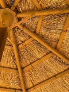 Detailed view of a straw roof with wooden beams, highlighting natural materials and craftsmanship.