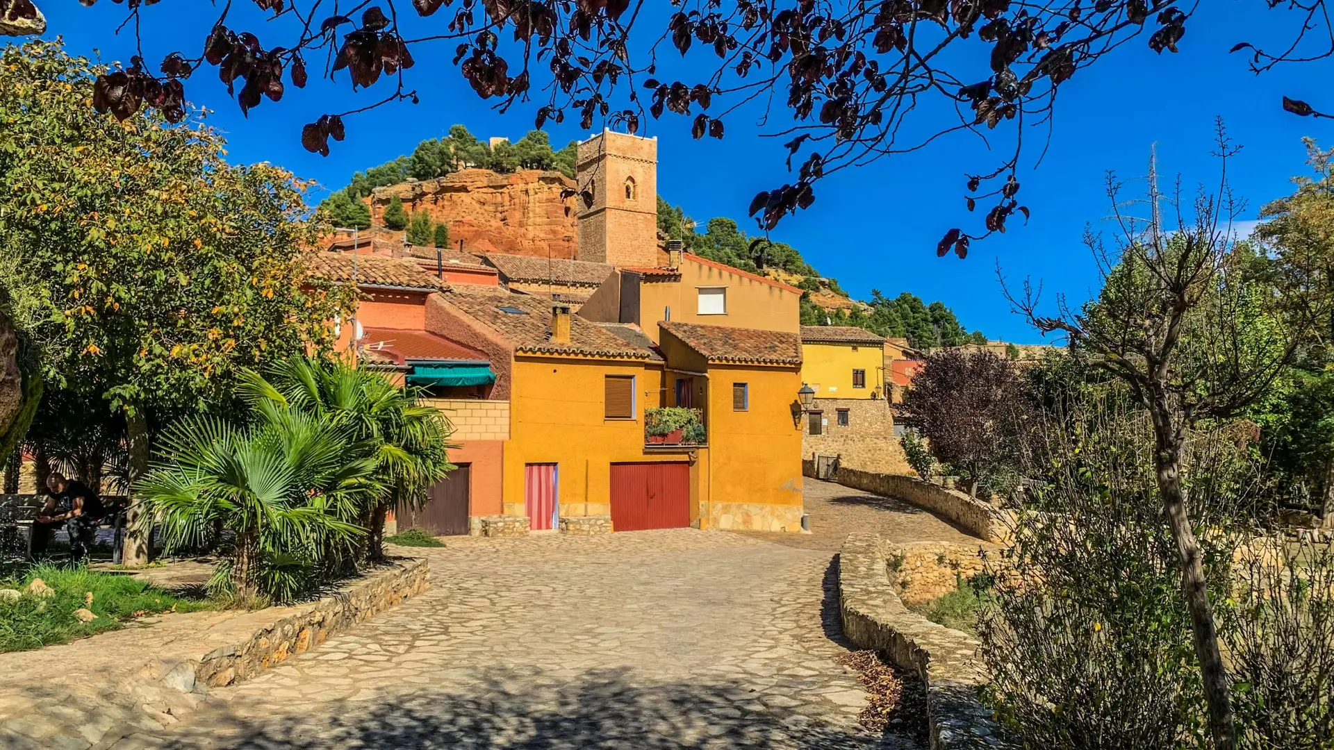 Charming Mediterranean village with vibrant buildings under clear blue sky.